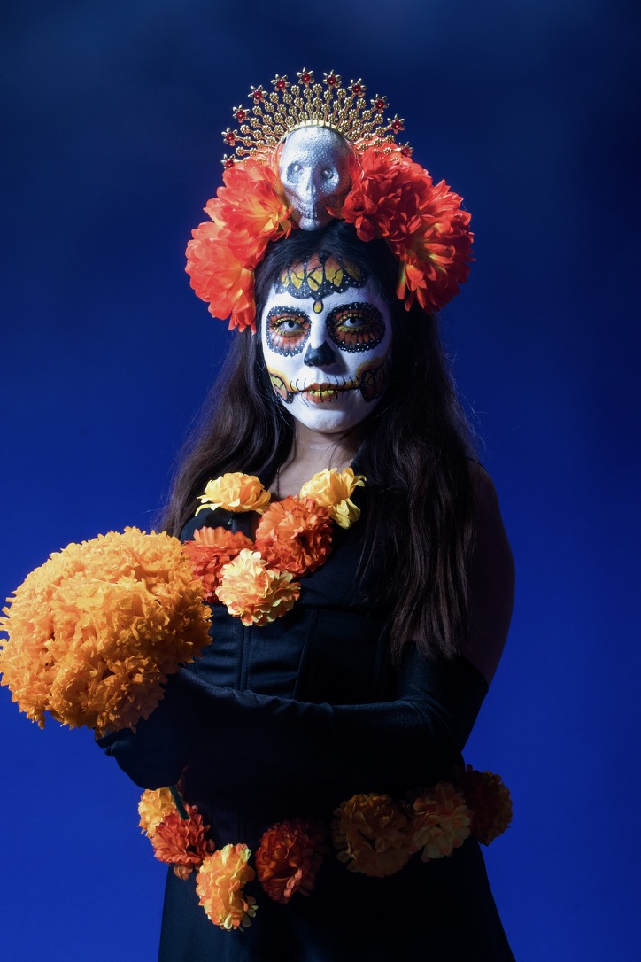 Retrato de catrina con flores naranjas sobre fondo azul